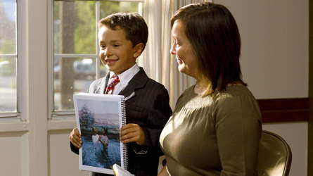 A young boy presenting a family hgme evening lesson with his mother's help