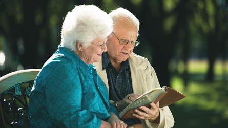 An elderly couple reading together