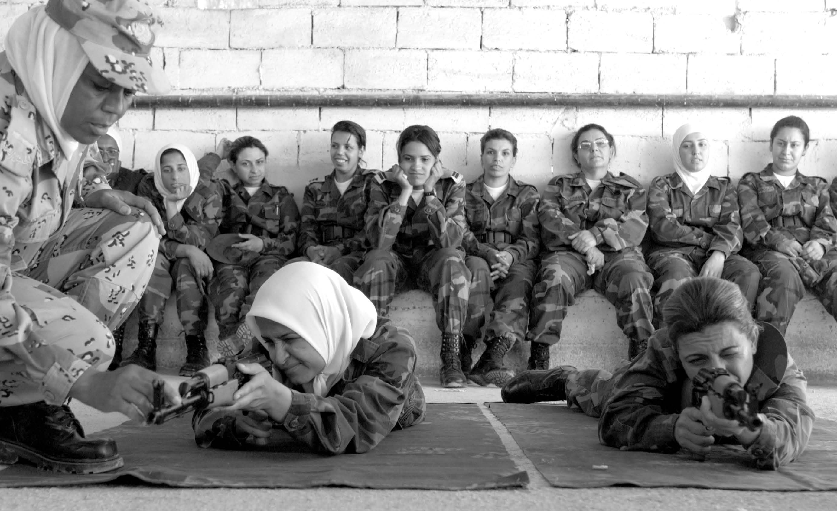 A Jordanian warrant officer instructs female trainees from the Iraqi army on proper techniques while firing an AK-47 as part of their basic training at the Jordanian Royal Military College during June 2004. Courtesy of DoD.