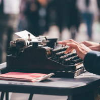 Hands typing on an old, manual typewriter
