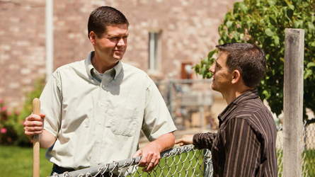 Two men talking over a fence