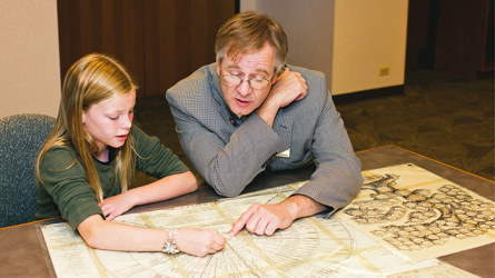 A father and daughter examining a fan-style pedigree chart