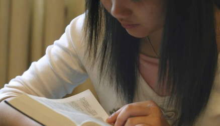 A student, her face in her book, as she studies the scriptures