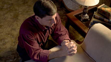 A man kneeling in prayer in his living room