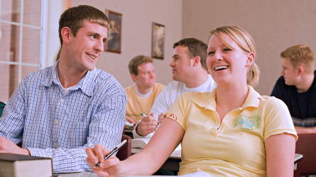A young adult man and woman in the classroom sharing happy conversation