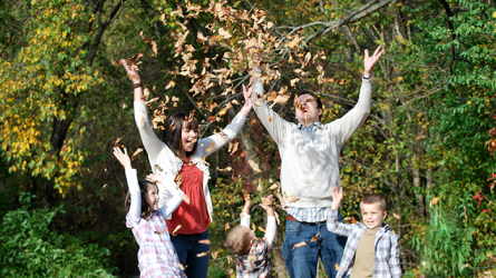 A family enjoying leaves falling after tossing a handful of them into the air