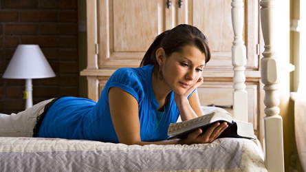 Woman on a bed studying the scriptures