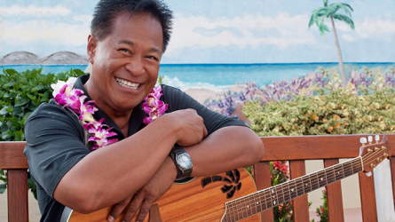Smiling island man with a lei and a guitar