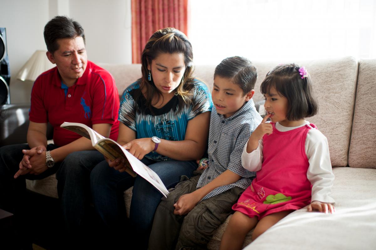 Parents and their two children looking at scripture stories together