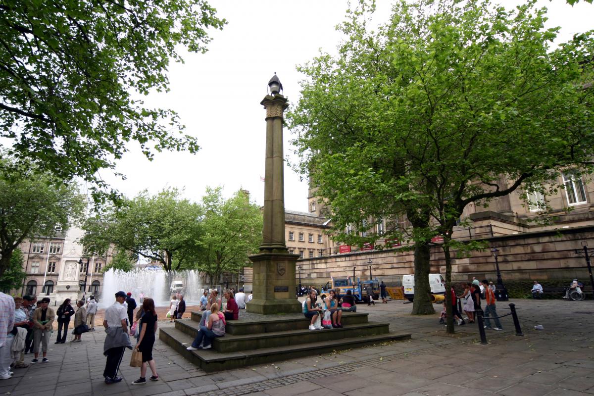 People in market square and obelisk in Preston, fountain in background