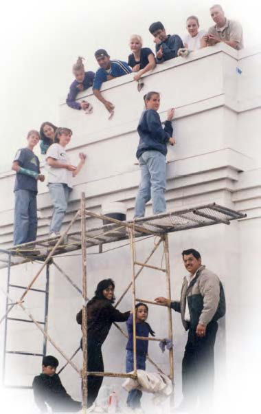 Youth and the Jaime and Hilda Beltran family cleaning temple’s marble exterior.