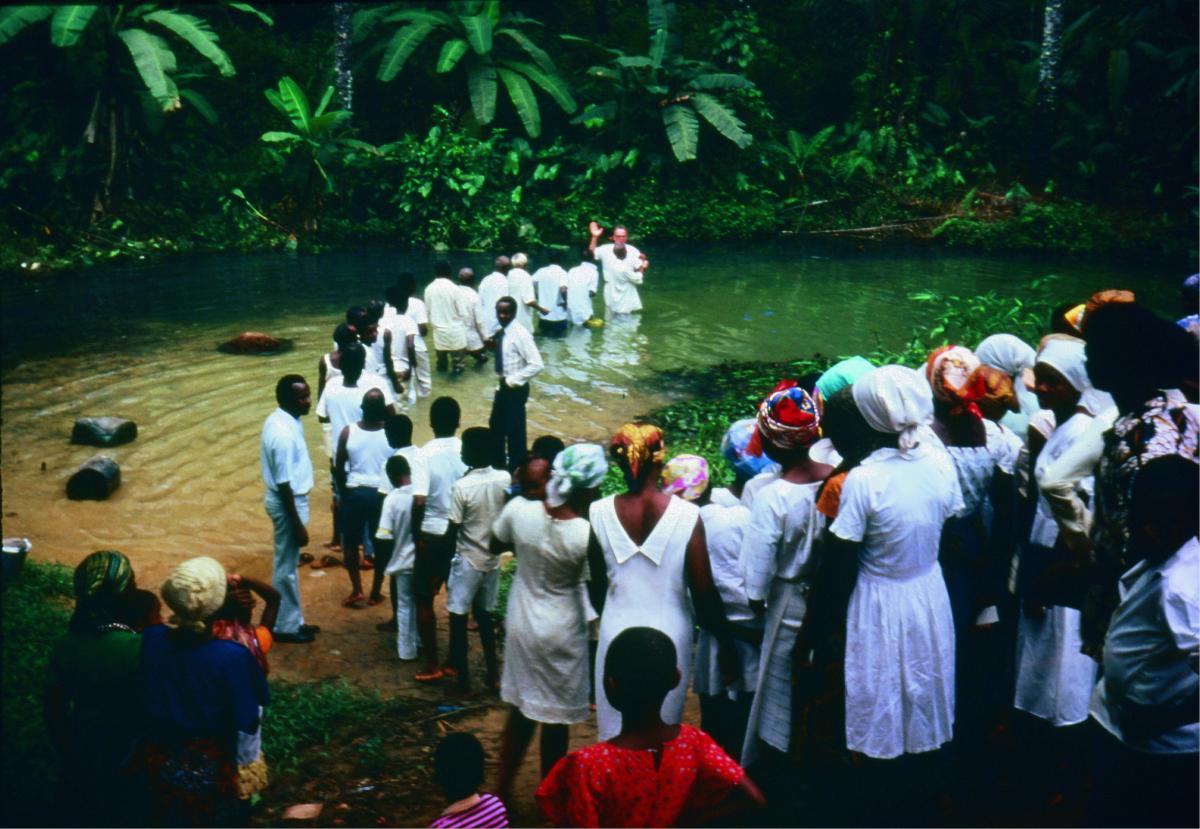 A group of West Africans in white being baptized
