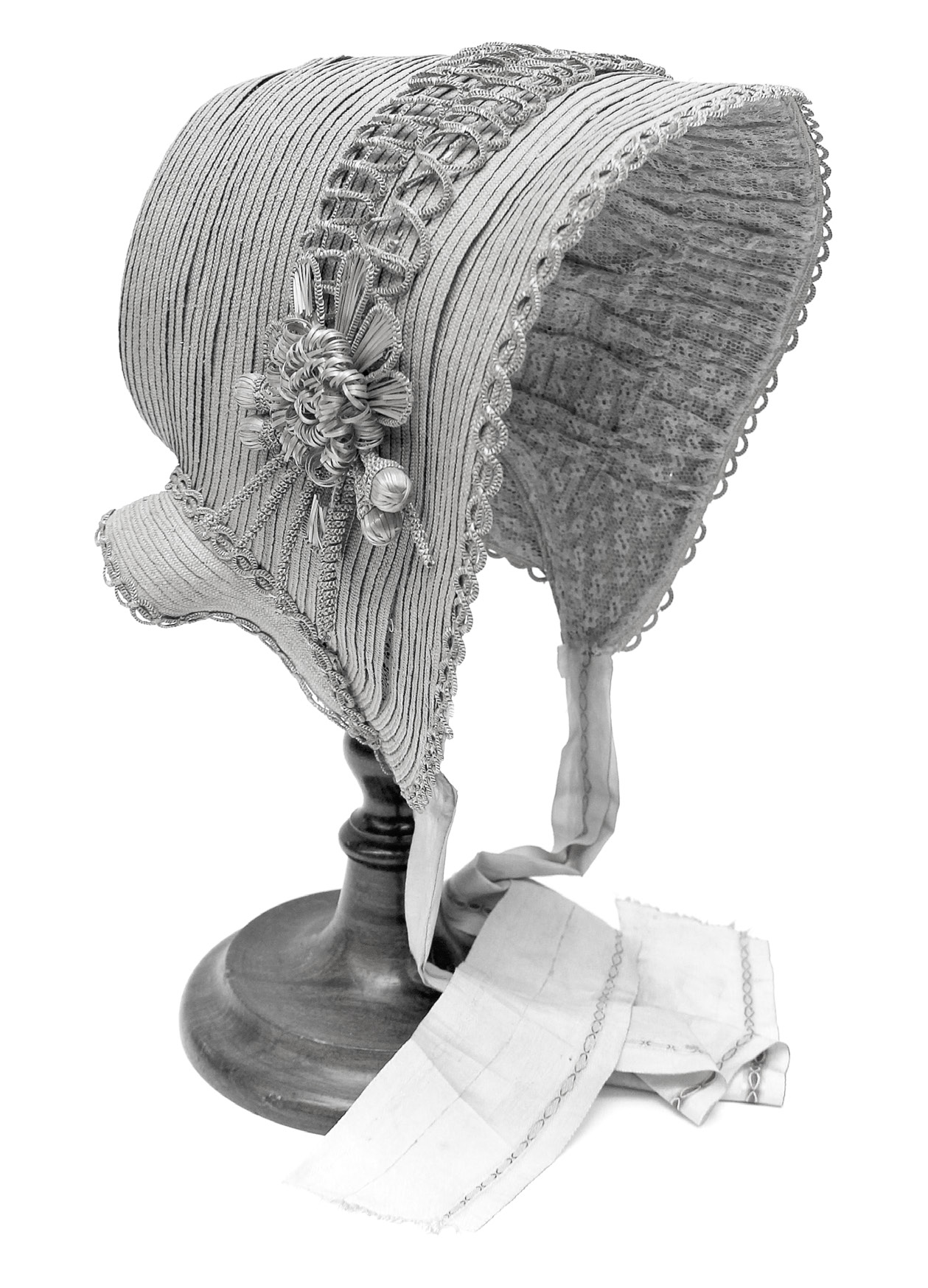 A ladies linen poke bonnet. The poke bonnet had a section behind the head, into which ladies could “poke,” or tuck their hair. This Dunstable-style hat typically featured a small crown with a wide and rounded front brim. The bonnet features narrow straw-braided trim across the top and around the edges with an extravagant straw flower. It belonged to Sarah Heller Conrad Bunnell. International Society Daughters of Utah Pioneers Picture Collection.