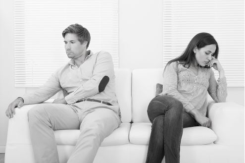 a couple sitting far apart on the couch