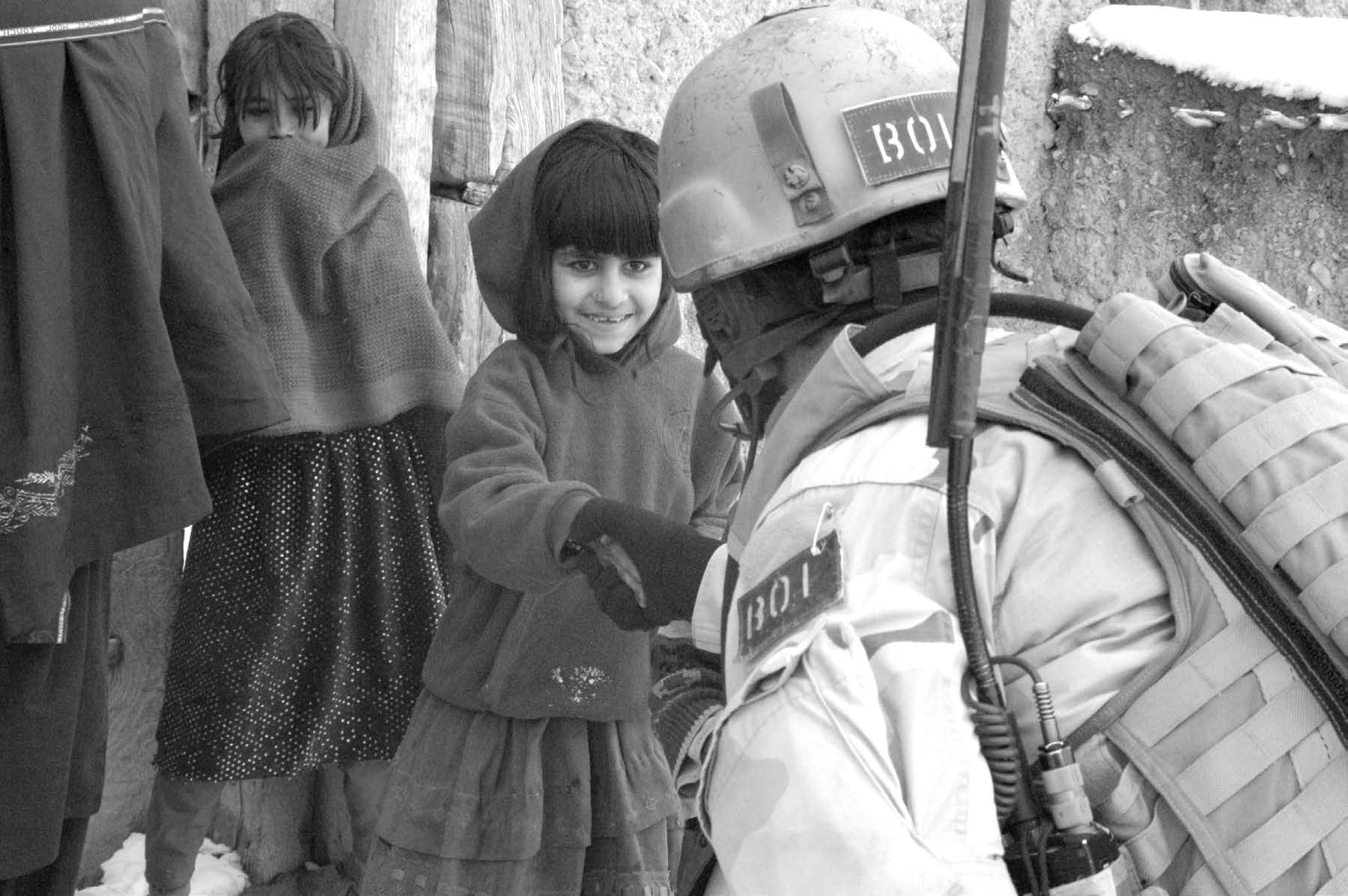 Colby Jenkins is shown shaking the hand of a young Afghan girl who lived in a nearby village. After the first snow of the winter arrived, they knew there would be many Afghans experiencing difficulties and suffering, so they ventured out to help where they could and took emergency supplies to those most in need. A piece of candy or something for the children was always well received. Courtesy of Colby Jenkins.