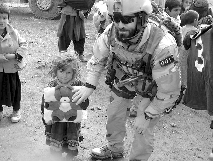 Colby Jenkins is pictured in 2005 walking a little Afghan girl to the front of the line to get her a little teddy bear pillow. Colby said, “I always sought out the little girls because I longed so much for my own two little ones. Helping these little Afghan girls and seeing them smile is what brought smiles to my face.” Courtesy of Colby Jenkins.