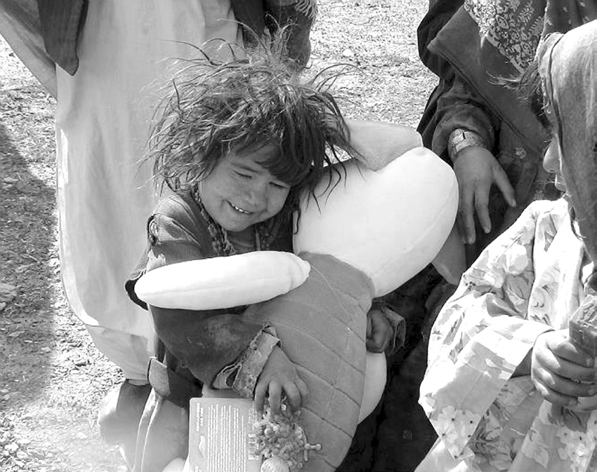 A young Afghan girl hugs a stuffed animal given to her through humanitarian packages from people in the United States in 2005. Courtesy of Colby Jenkins.