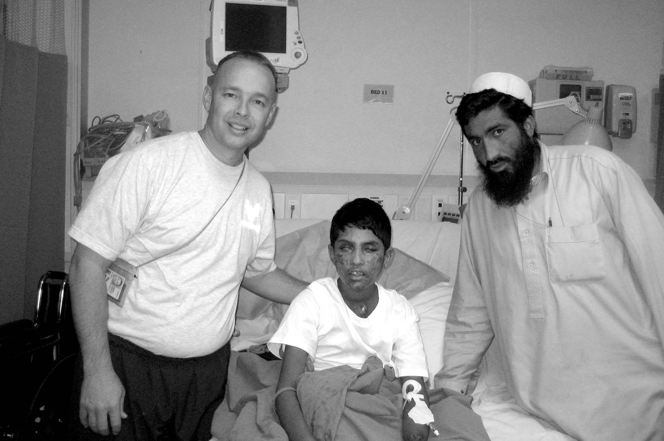 Dr. Blaine Tuft (left) at Hamed Hilal’s bedside with Hamed’s uncle while he continued to receive care at Craig Joint Theater Hospital. Courtesy of Blaine Tuft.