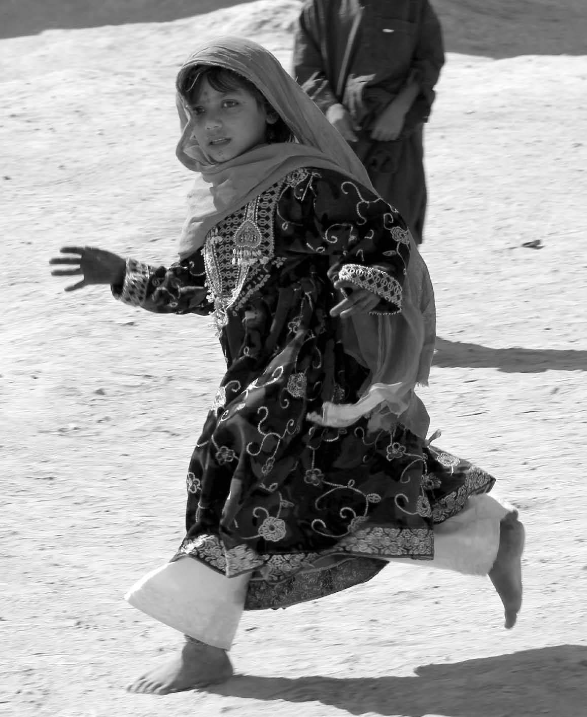 A barefoot Afghan girl scurries away from American soldiers who were patrolling her village. Courtesy of J. Joseph DuWors.