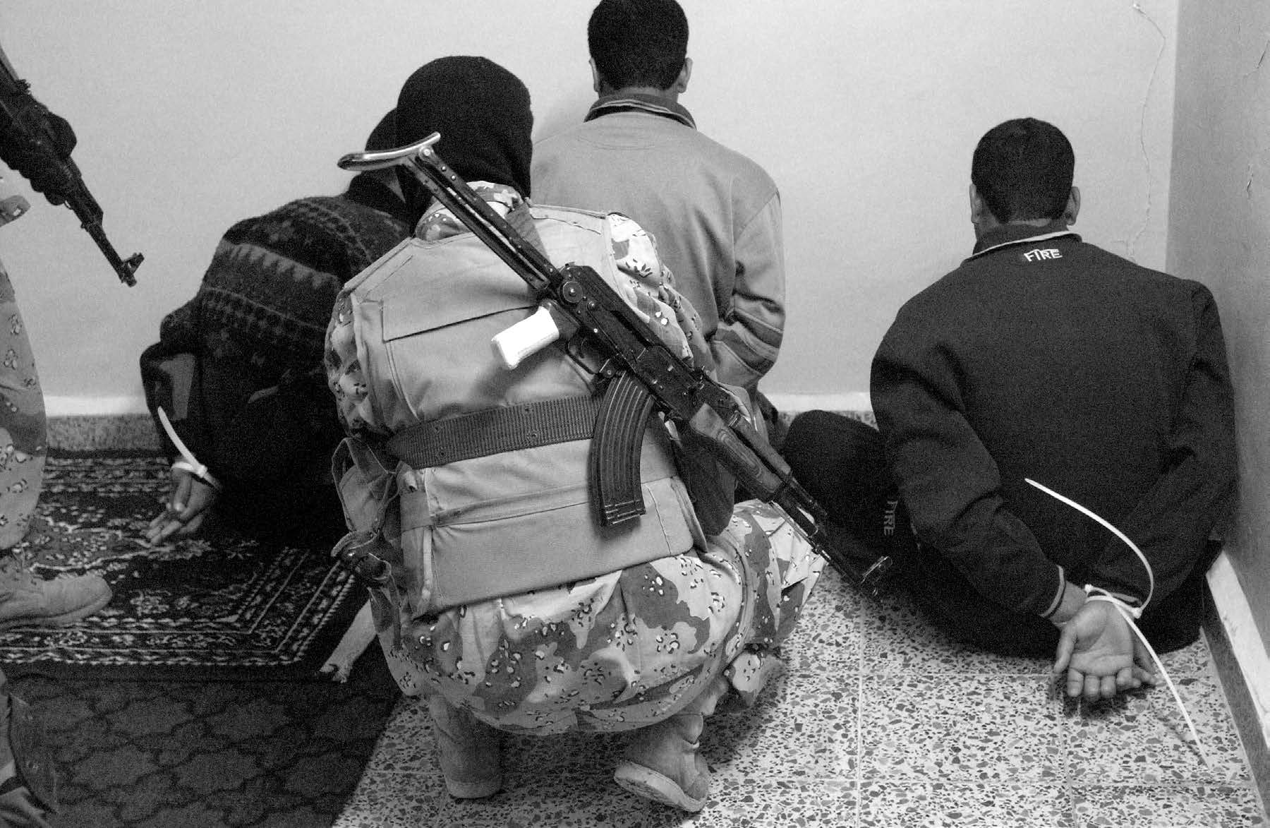 An Iraqi soldier secures three suspected insurgents after a raid near Kirkuk, Iraq, on March 17, 2005. Courtesy of DoD.