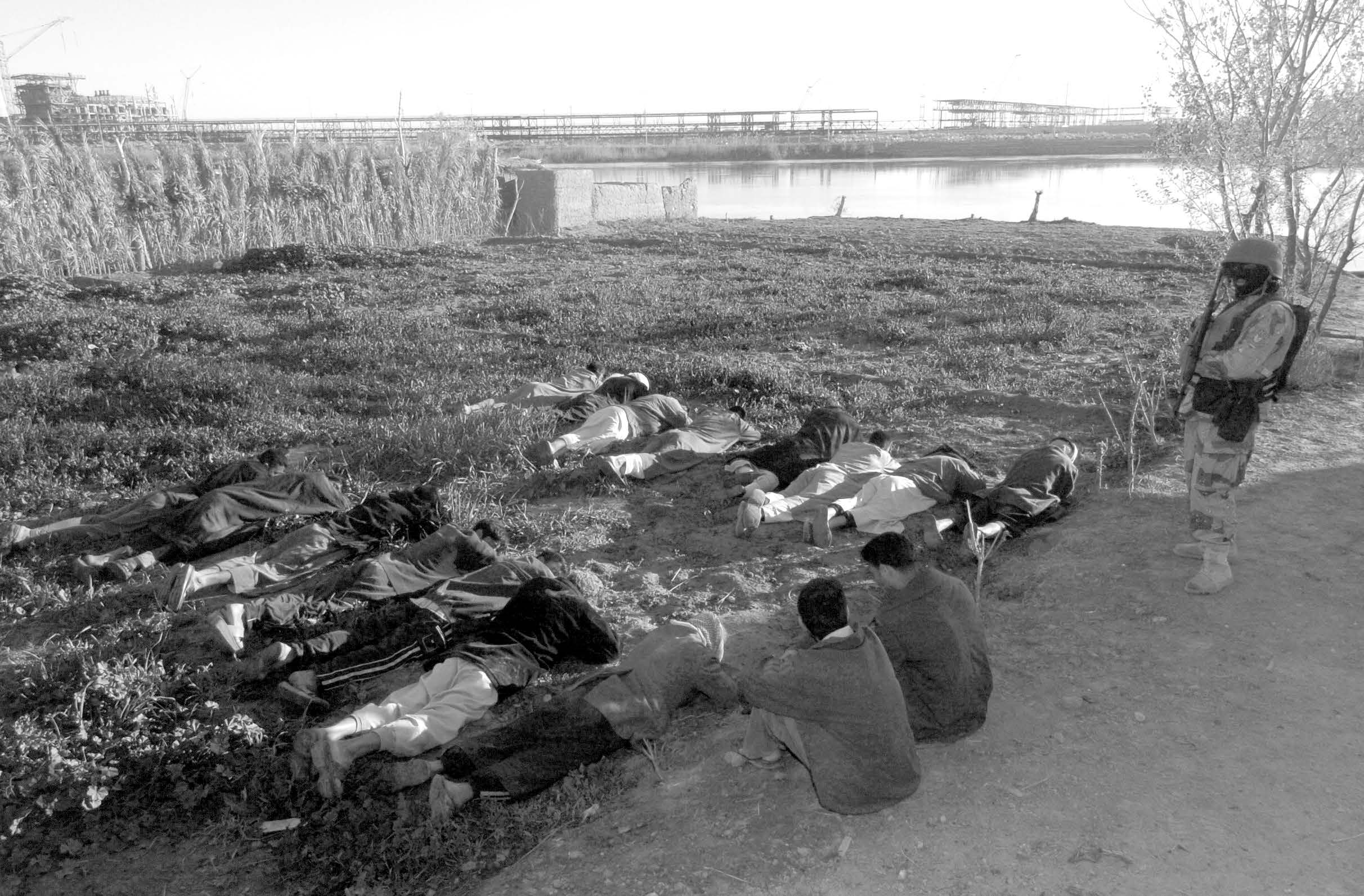 Suspected insurgents are assembled in a field as members of Iraqi National Guard, together with U.S. Army escorts, search the suspected insurgent’s homes during a raid in Babil Province, Iraq, on March 25, 2005. Courtesy of DoD.