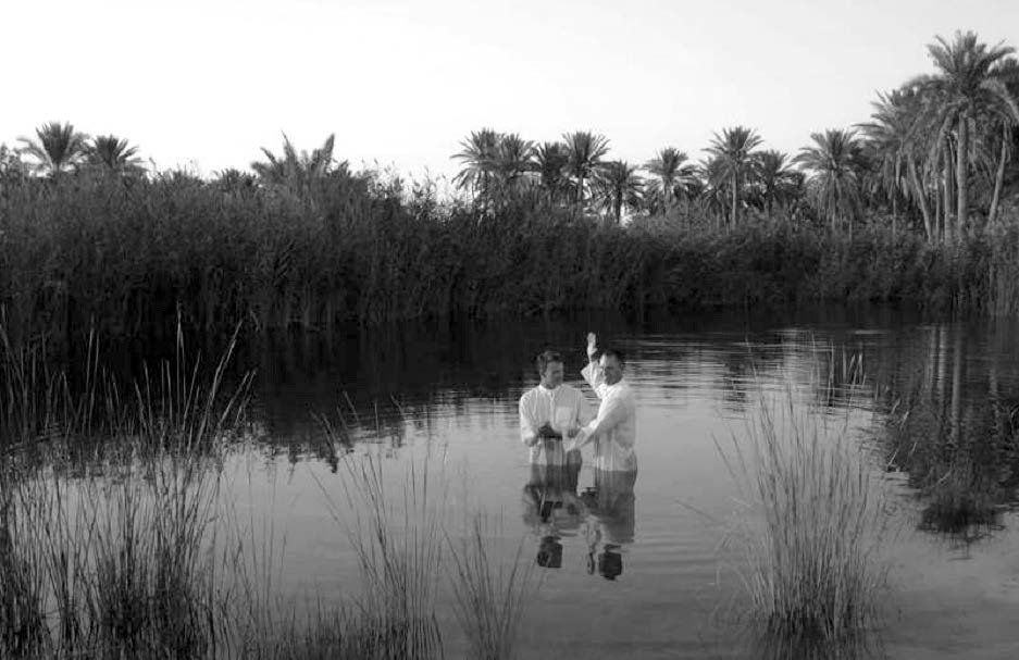 A Latter-day Saint service member of the 3rd Armored Cavalry Regiment baptizes Sergeant Kevin Wood in an oasis in the Al Anbar province. Courtesy of Steve Gundry.