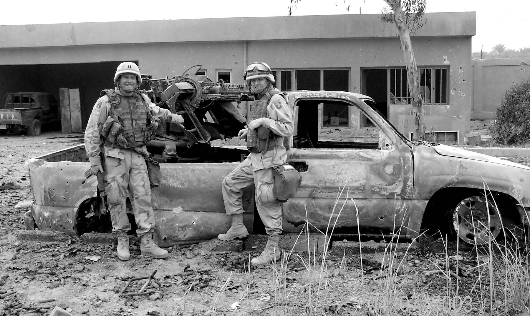 Colonel Richard Hatch (right) is pictured with one of his subordinates in front of a damaged Iraqi vehicle. Courtesy of Richard O. Hatch.