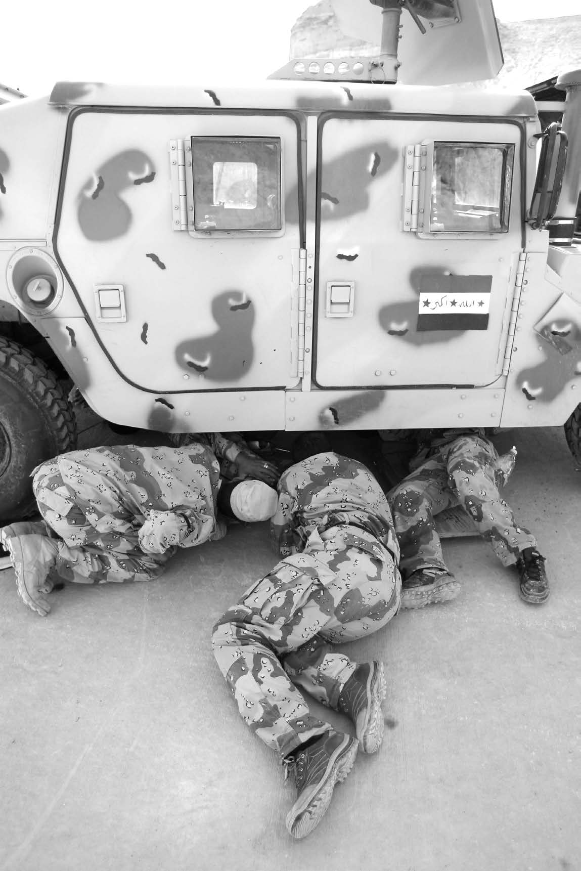 Iraqi army soldiers examine the underside of a Humvee as they learn high-mobility multiwheeled vehicle maintenance during a class in Al Anbar, Iraq, during March 2006. Courtesy of DoD.