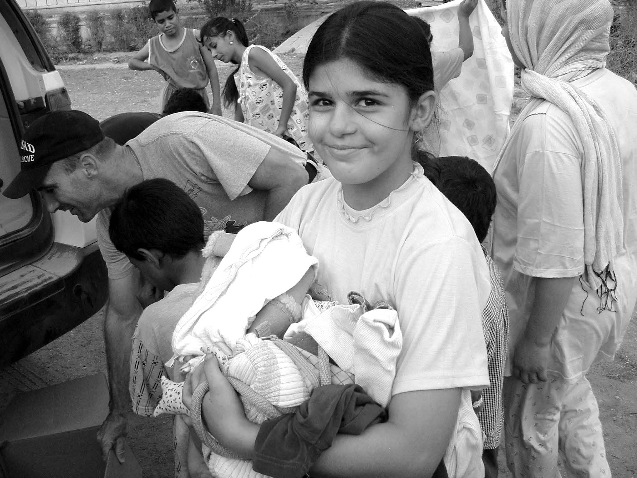 A smiling Iraqi girl carrying clothes donated by American supporters. Courtesy of Michael McMaken.