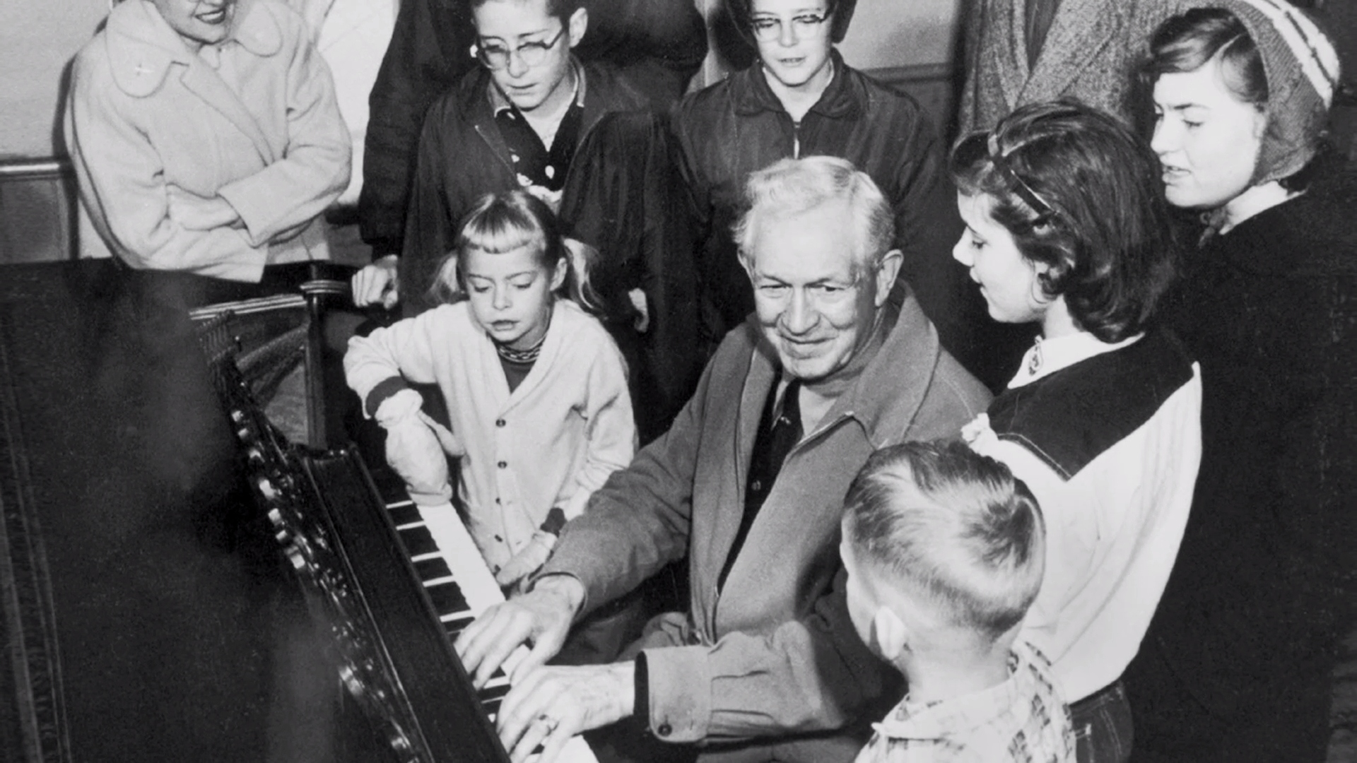 David O McKay playing the piano surrounded by family members