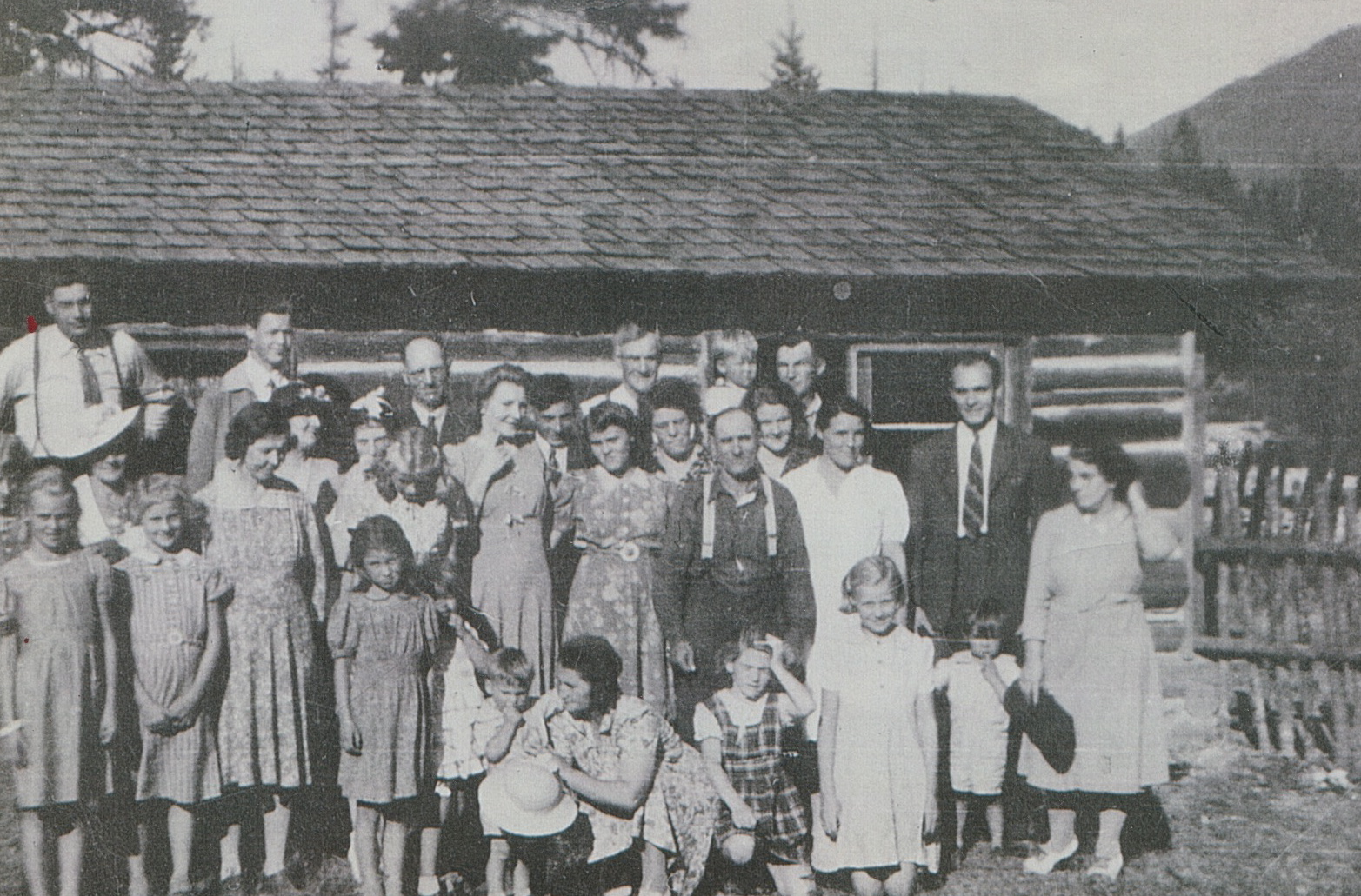 members in front of a log cabin