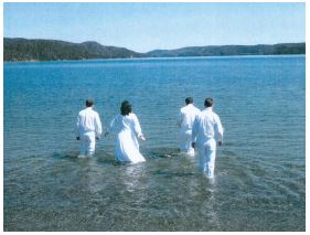 four people dressed in white going into the water