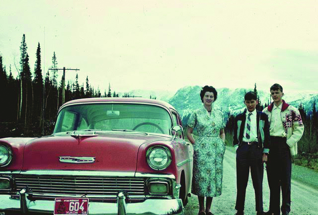 three adults with a red car