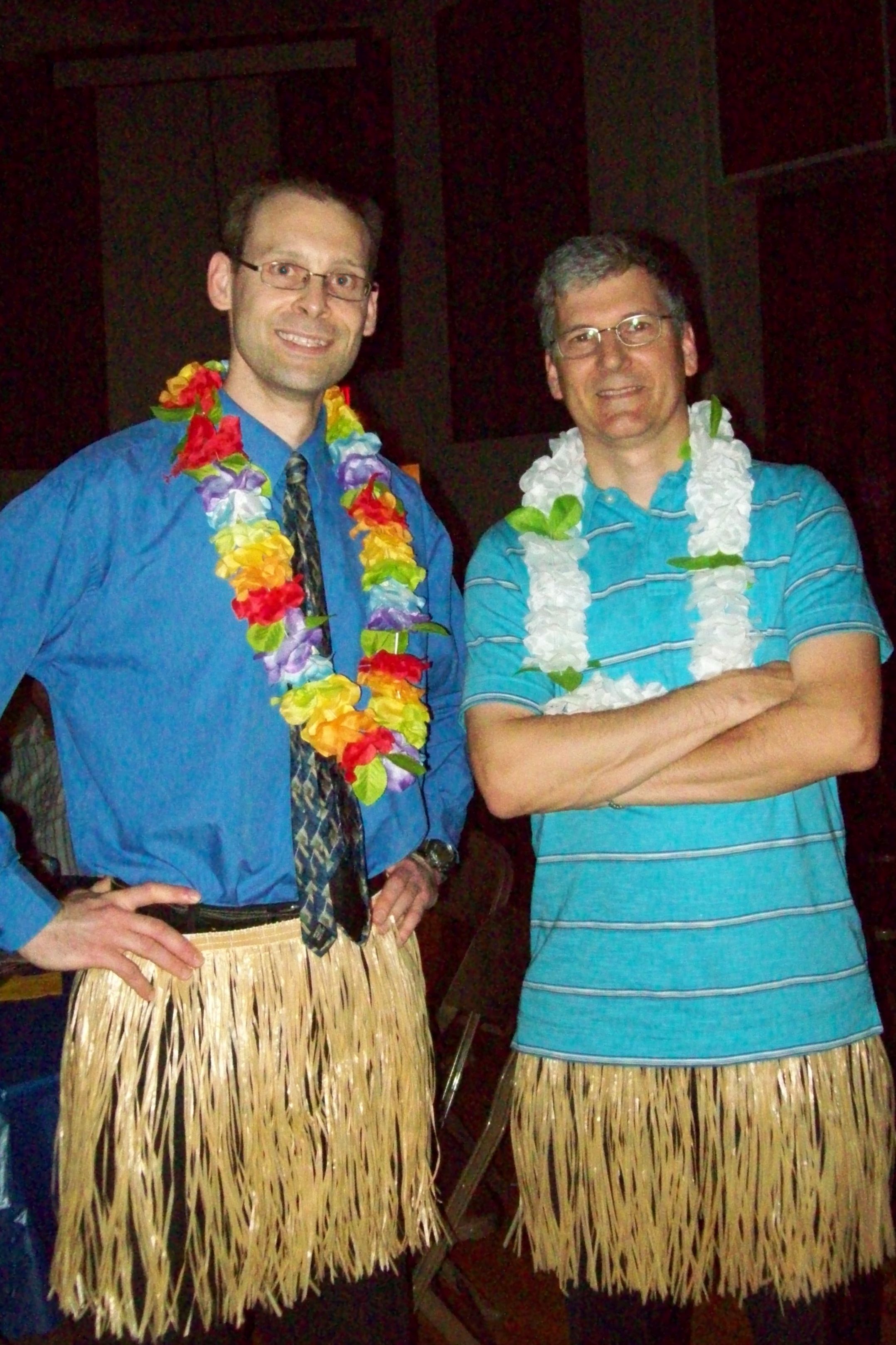 two men with hula skirts and leis