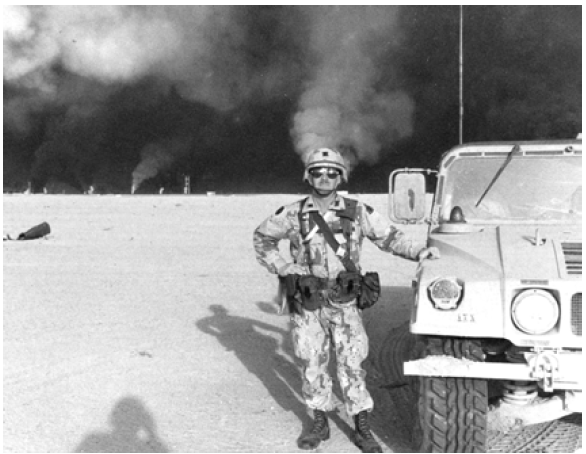 Combat artist Lieutenant Colonel Frank Thomas with burning oil field fires in the background, north of Kuwait City on March 20, 1991. Courtesy of Frank M. Thomas.