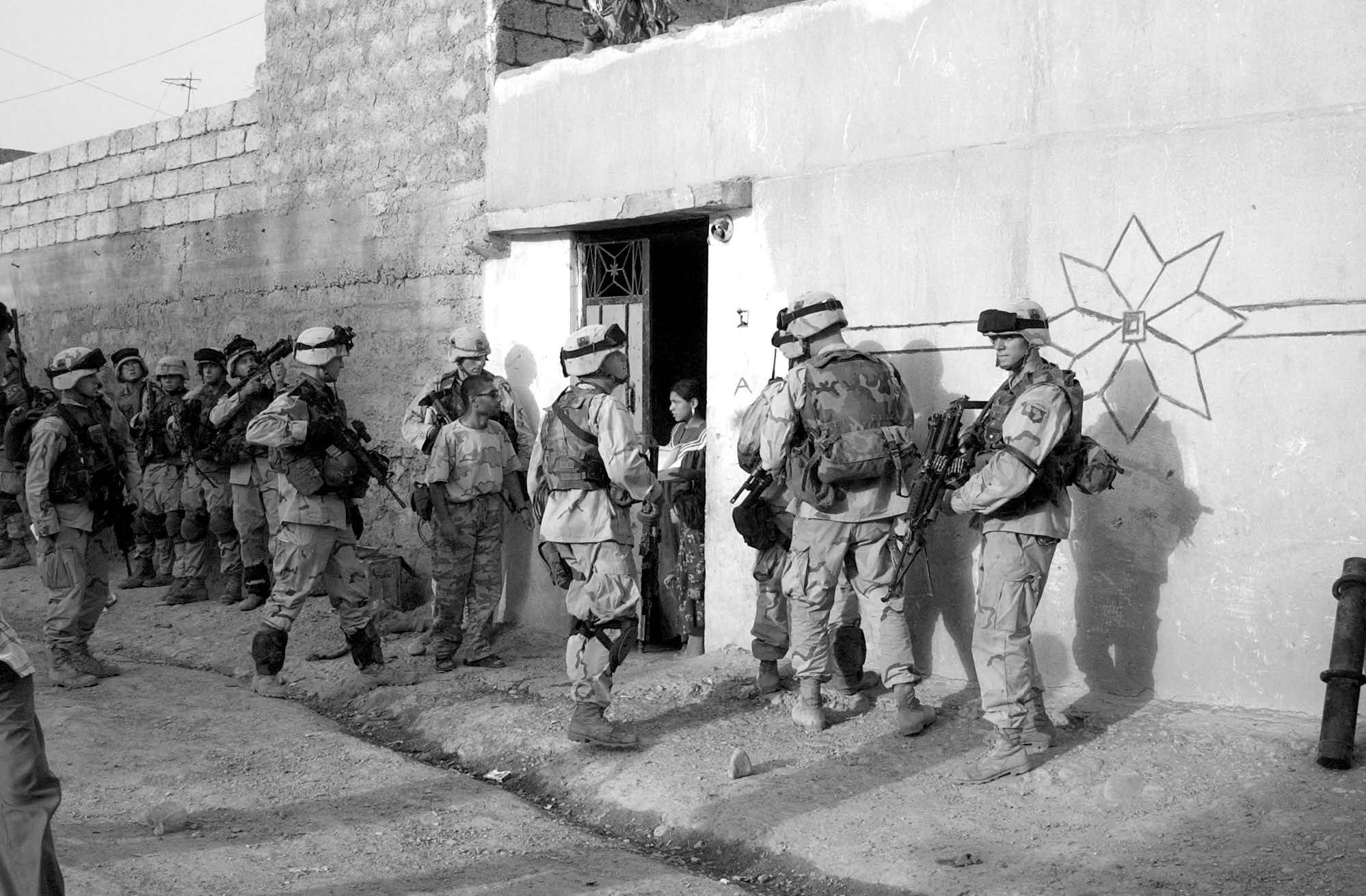 Soldiers from the 101st Airborne Division move from house to house conducting searches looking for weapons in Mosul, Iraq, on June 18, 2003. Courtesy of DoD.