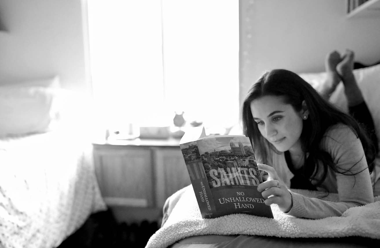 Girl on a bed reading Saints
