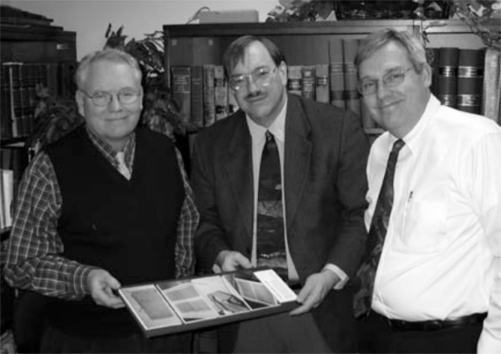 Ray L Huntington (left) and Brian M. Hauglid (right) visit with Ronald E. Romig (center)