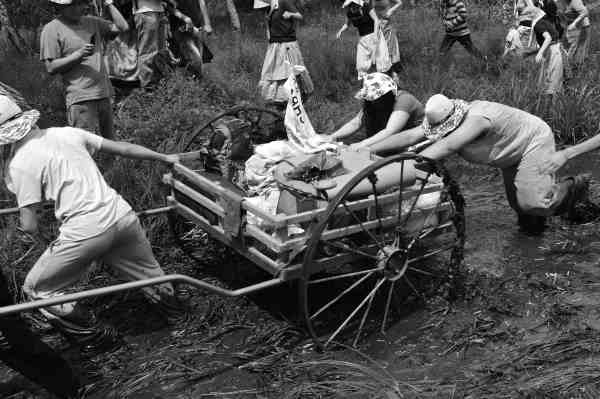 photo of youth pulling a handcart through mud