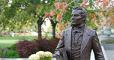 Statue of Joseph Smith with trees and floral background